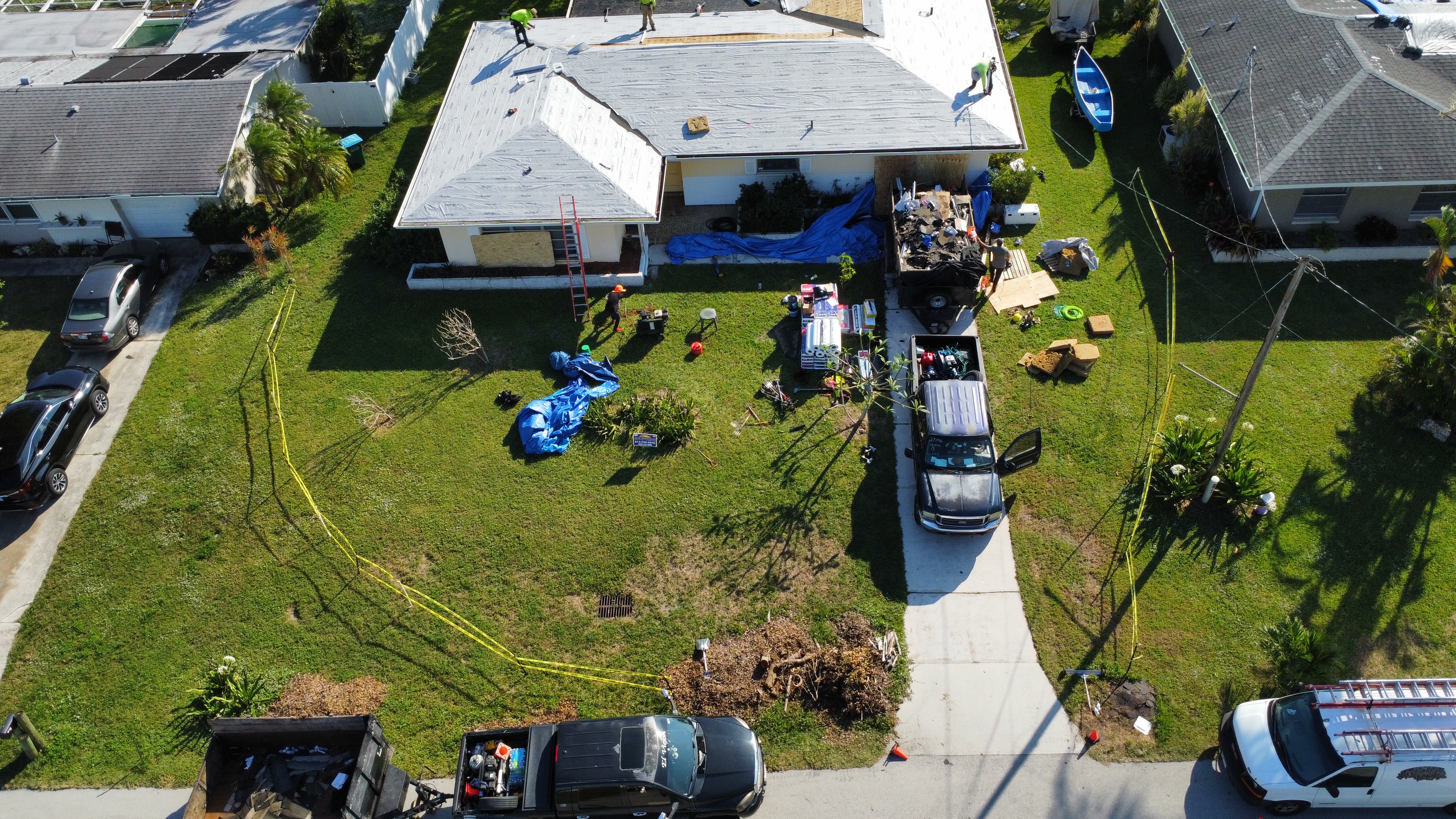 Multiple roofers installing shingles on a suburban home